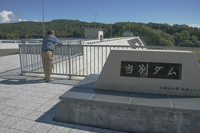 「流域の自然を考えるネットワーク」の宮崎司代表。すぐ脇には高橋はるみ北海道知事名の石が置かれていた。