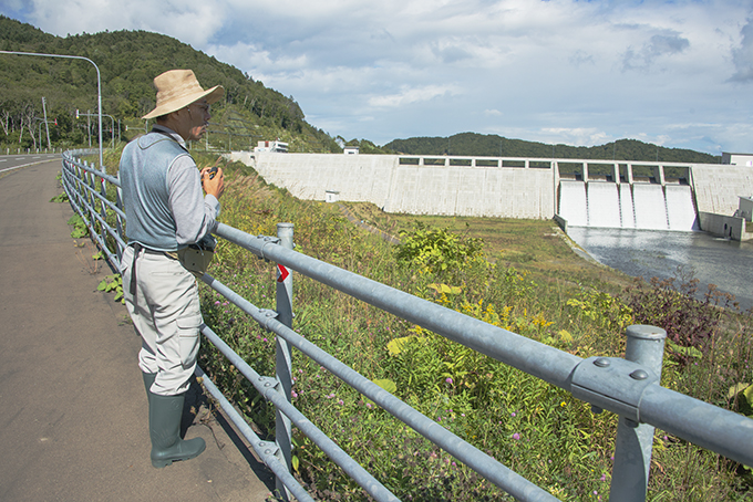 長野県の「渓流保護ネットワーク」の田口康夫氏も現地視察した。後ろは完成した当別ダム